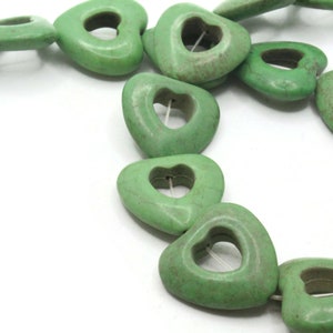 May include: A strand of green heart-shaped beads with a hole in the center of each bead. The beads are made of a natural stone, possibly turquoise.