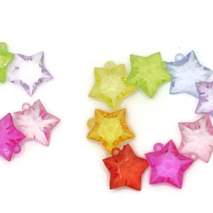 May include: Assortment of ten colorful star-shaped charms made of clear plastic. The charms are in various shades of pink, purple, yellow, orange, and green.