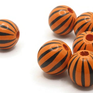 May include: Orange wooden beads with black stripes. The beads are round with a hole drilled through the center. The beads are a bright orange color with evenly spaced black stripes. These beads are ideal for jewelry making and crafts.