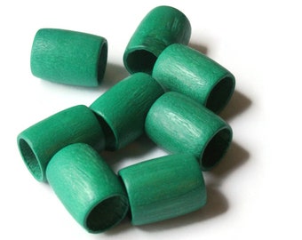 May include: A group of eight green wooden beads, each with a cylindrical shape and a smooth, slightly textured surface. The beads are arranged in a loose pile, with some overlapping.