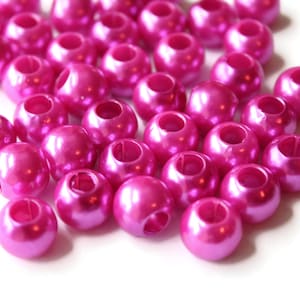 May include: A pile of bright pink plastic beads with a hole in the center of each bead. The beads are smooth and shiny.