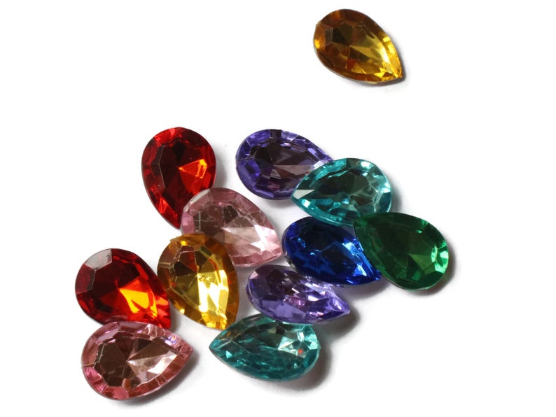 May include: Assortment of colorful teardrop-shaped glass rhinestones in various shades of red, pink, blue, green, purple, and yellow.