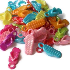 May include: A pile of colorful plastic flip-flop charms with metal rings. The charms are in various colors, including pink, purple, blue, green, yellow, and orange.