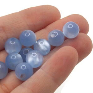 May include: A collection of light blue round beads with a frosted finish.