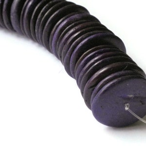 May include: A strand of dark purple round beads, stacked and strung on a clear thread.