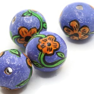 May include: Four spherical beads with a speckled periwinkle blue base color. Each bead features a hand-painted design of orange flowers with black outlines and green stems with leaves. Each bead has a central hole for stringing purposes.