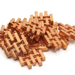 May include: A group of copper-colored metal charms in the shape of a traditional Chinese double happiness symbol. The charms are intricately designed with a lattice pattern.