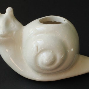 May include: White ceramic snail planter with a textured shell and a hole in the top for planting.