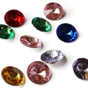 May include: Assortment of ten round, faceted glass gems in various colors, including red, green, blue, pink, and purple. The gems are arranged in a random pattern on a white background.