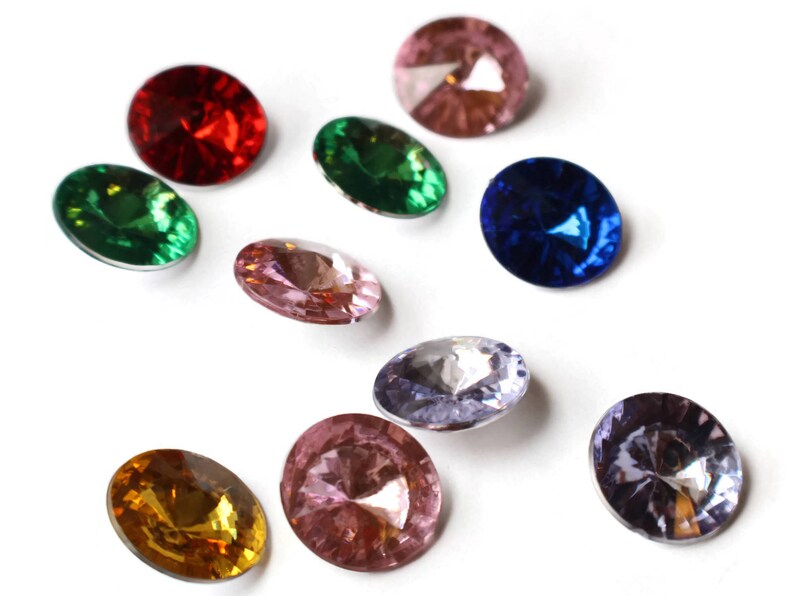 May include: Assortment of ten round, faceted glass gems in various colors, including red, green, blue, pink, and purple. The gems are arranged in a random pattern on a white background.