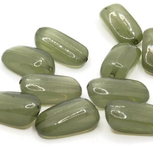 Op de afbeelding: Tien ondoorzichtige groene glazen kralen, elk met een iets andere vorm en grootte. De kralen zijn glad en hebben een subtiele glans.