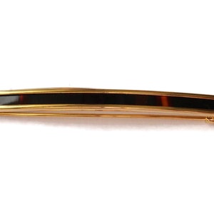 May include: A gold hair clip with a black and brown tortoiseshell insert.