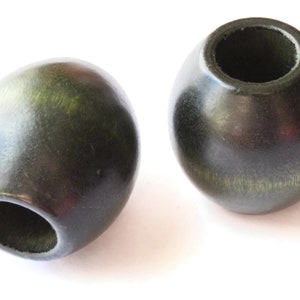 May include: Two dark green wooden beads with a hole in the center. The beads are smooth and have a slight sheen.