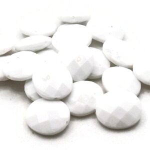 May include: A pile of white oval-shaped beads with a faceted finish.