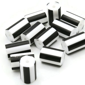 May include: A group of black and white striped cylindrical beads. The beads are made of plastic and have a smooth, glossy finish.