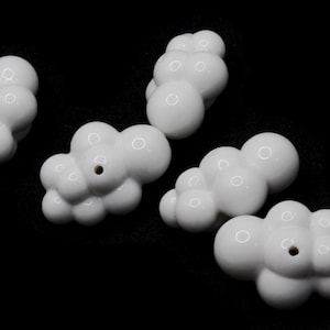 May include: Five white ceramic cloud-shaped incense holders with small holes in the centre.