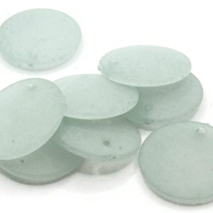 May include: A group of eight round, frosted glass beads in a light blue color. The beads are smooth and have a slightly textured surface.