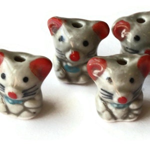 May include: Four ceramic mouse beads with red ears, gray bodies, and black eyes. Each bead has a small hole for stringing.