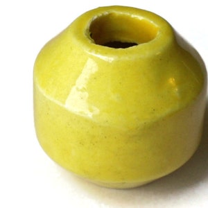 May include: A small, bright yellow ceramic vase with a rounded shape and a smooth, glossy finish.
