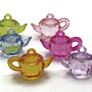 Puede incluir: Seis teteras de plástico de colores con un diseño facetado. Las teteras son en tonos de verde, azul, rosa, morado y amarillo.