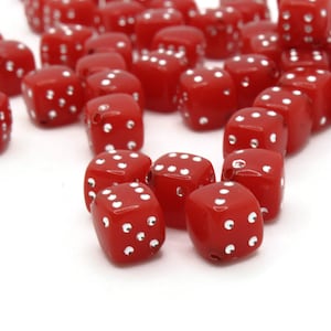 Może przedstawiać: Grupa czerwonych kostek do gry z białymi kropkami rozrzuconych na białym tle. Kostki są wykonane z plastiku i mają błyszczące wykończenie.