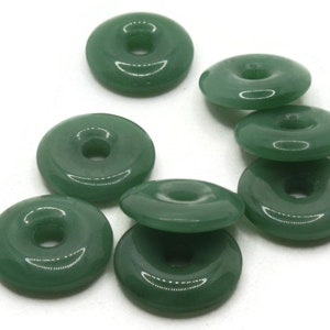 May include: Eight green jade donut beads with a hole in the center. The beads are smooth and polished.