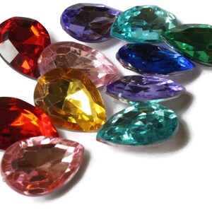 May include: Assortment of teardrop-shaped glass rhinestones in various colors, including red, pink, gold, green, blue, and purple.