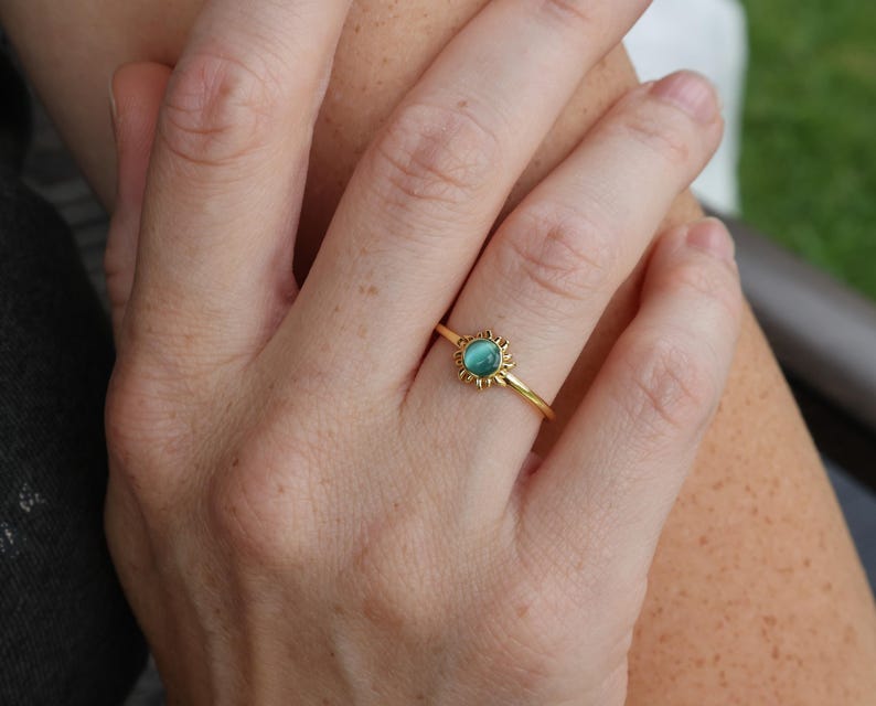 May include: A gold ring with a turquoise gemstone set in a sunburst design.
