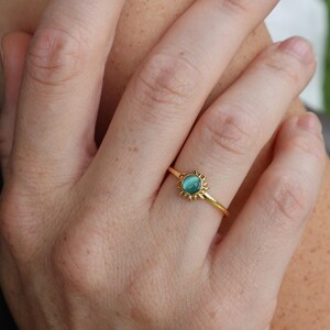May include: A gold ring with a turquoise gemstone set in a sunburst design.