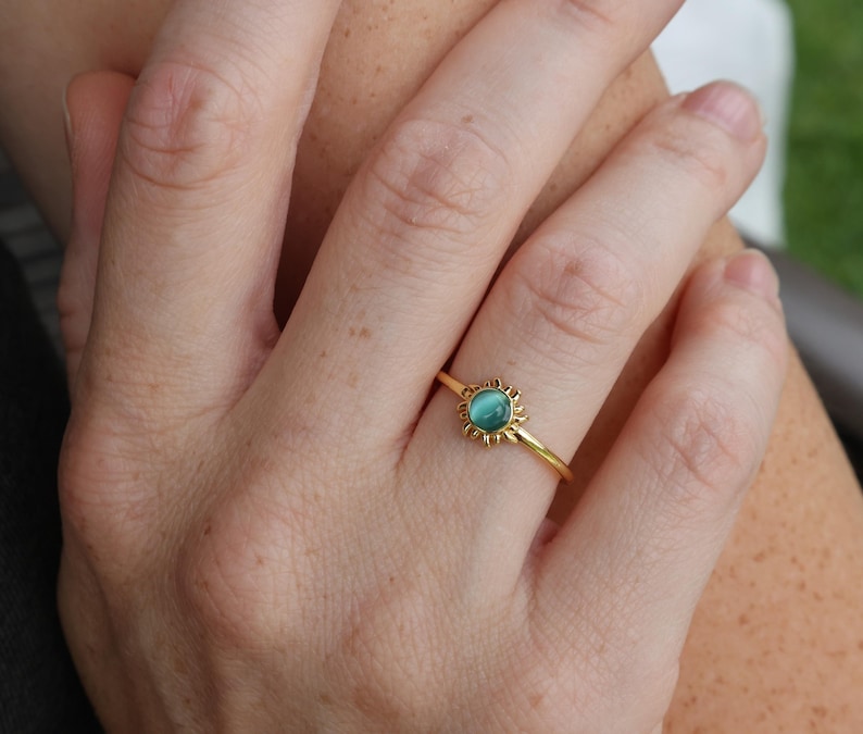 May include: A gold ring with a turquoise gemstone set in a sunburst design.
