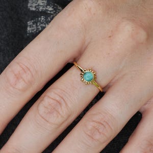 May include: A gold ring with a turquoise gemstone set in a sunburst design.