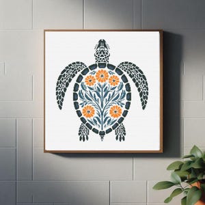 Op de afbeelding: Een ingelijst kruissteekontwerp van een blauwe en witte schildpad met oranje bloemen in het midden van zijn schild.