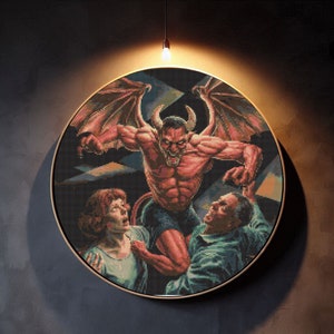 Può includere: Un'opera d'arte a punto croce incorniciata che raffigura un demone rosso con ali e corna, che tiene una figura umana nelle sue grinfie. Il demone sta attaccando un uomo barbuto che indossa una camicia blu. L'opera d'arte è su uno sfondo scuro.