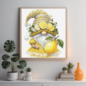 May include: A yellow gnome wearing a white and yellow striped hat, a yellow dress with white lace trim and holding a large yellow lemon. The gnome has a wreath of lemons and white flowers around its head.