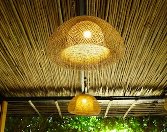 May include: Three woven wicker pendant lights hang from a bamboo ceiling. The lights are round and have a natural, light brown color.