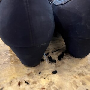 K&ouml;nnte beinhalten: Ein Paar marineblaue Keilabsatzschuhe. Die Schuhe haben eine abgerundete Spitze und ein strukturiertes Obermaterial. Der Keilabsatz ist etwa 5 cm hoch. Die Schuhe stehen auf einer hellbraunen Oberfl&auml;che.