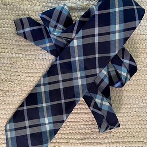 May include: A navy blue tie with a white and light blue plaid pattern.