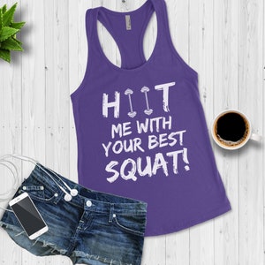 May include: Purple tank top with a white graphic that says "HIIT ME WITH YOUR BEST SQUAT!" The graphic includes a dumbbell icon.