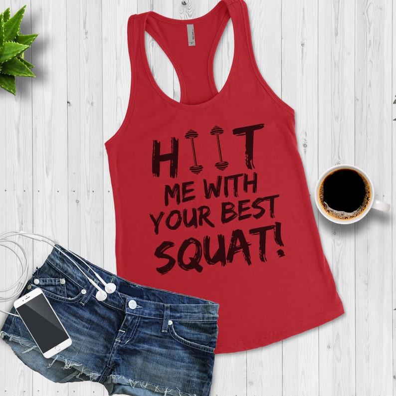 May include: Red tank top with a black graphic that says "HIIT ME WITH YOUR BEST SQUAT!" The graphic includes two small dumbbell icons.
