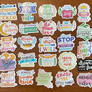 May include: A set of 24 colorful stickers with inspirational quotes and phrases. The stickers feature a variety of fonts, colors, and designs, including flowers, hearts, and stars. Some of the quotes include "Be You Not Them", "Happy Mind Happy Life", "Do What You Love", "Turn I Wish Into I Will", "You Matter The Most", "Your Only Limit Is You", "Dream Without Fear", "Positive Mind Vibes", and "Speed Doesn't Matter Forward Is Forward".
