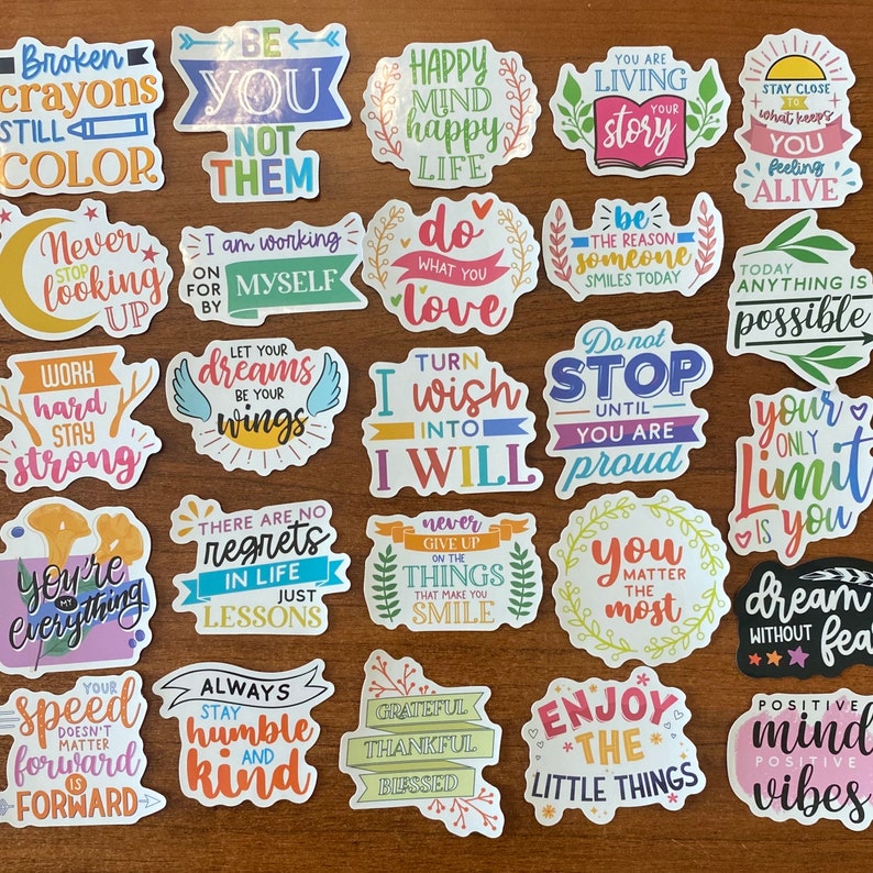 May include: A set of 24 colorful stickers with inspirational quotes and phrases. The stickers feature a variety of fonts, colors, and designs, including flowers, hearts, and stars. Some of the quotes include "Be You Not Them", "Happy Mind Happy Life", "Do What You Love", "Turn I Wish Into I Will", "You Matter The Most", "Your Only Limit Is You", "Dream Without Fear", "Positive Mind Vibes", and "Speed Doesn't Matter Forward Is Forward".