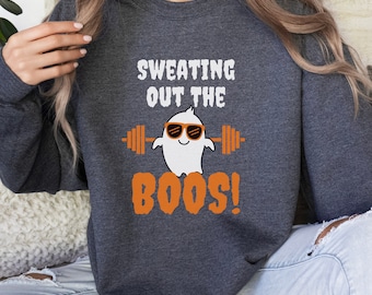 May include: A dark gray sweatshirt with a white ghost wearing sunglasses and lifting a barbell. The text "SWEATING OUT THE BOOS!" is printed in orange.