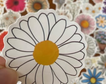 May include: A white daisy sticker with a yellow center and black outline. The sticker is surrounded by other flower stickers.