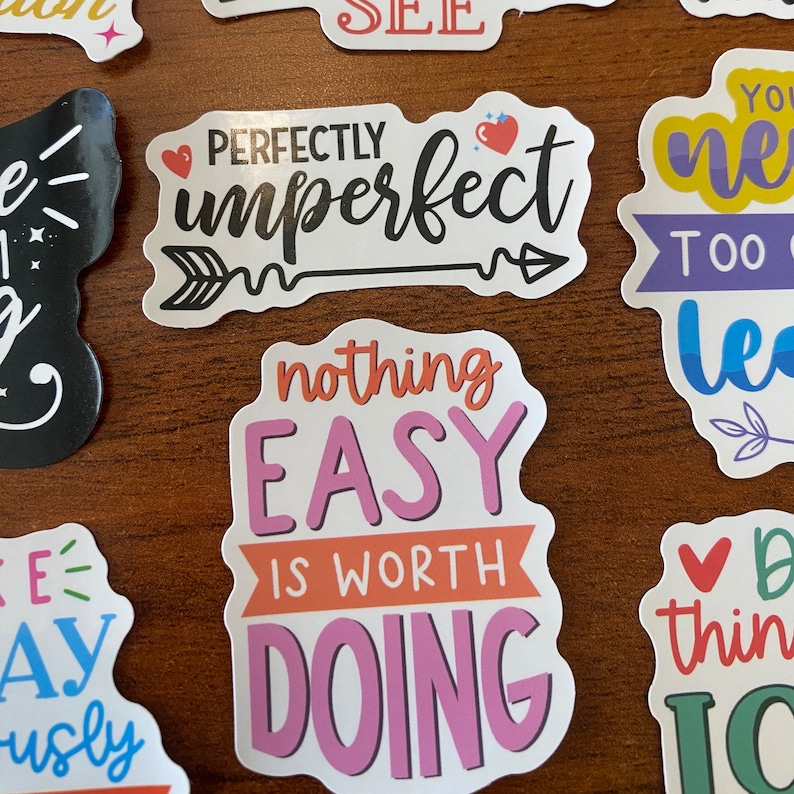 May include: A set of colorful stickers with motivational quotes. The stickers feature phrases like "Perfectly Imperfect", "Nothing Easy Is Worth Doing", and "You Never Learn Too Late".