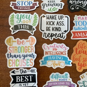May include: A set of 12 colorful motivational stickers with positive messages. The stickers feature phrases like "You Only Fail When You Stop Trying", "Keep Going Keep Growing", "Prove Them Wrong", "You Got This", "Wake Up Kick Ass Be Kind Repeat", "Make Today Ridiculously Amazing", "Be Stronger Than Your Excuses", "Creativity Is Intelligence Having Fun", "Life Is Tough But So Are You", "The Best Is Yet To Come", "Difficult Roads Often Lead To Beautiful Destinations", and "Be Yourself".