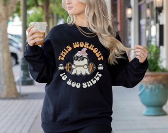 May include: Black sweatshirt with a white ghost wearing a witch hat and sunglasses lifting a barbell. The text "This workout is boo sheet" is printed on the sweatshirt.
