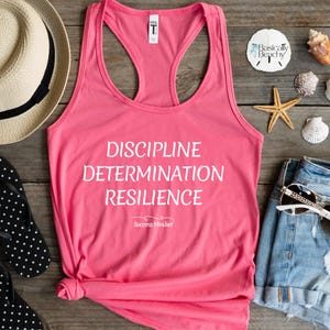 May include: Pink tank top with the words "Discipline Determination Resilience" and the phrase "Success Mindset" in white text.