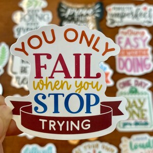 May include: A white sticker with a motivational quote in colorful lettering. The quote reads "You only fail when you stop trying".