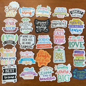 May include: A collection of 20 colorful stickers with motivational quotes and phrases. The stickers feature a variety of fonts, colors, and designs, including hearts, stars, and arrows. Some of the quotes include "Slay the Day", "Be the Change", "Do all things with Love", and "Life is tough but so are you".