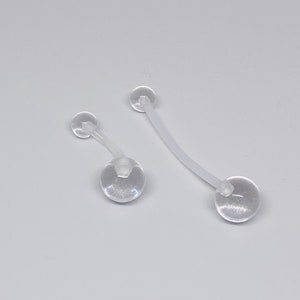 May include: Two clear plastic belly button rings with round balls on each end.